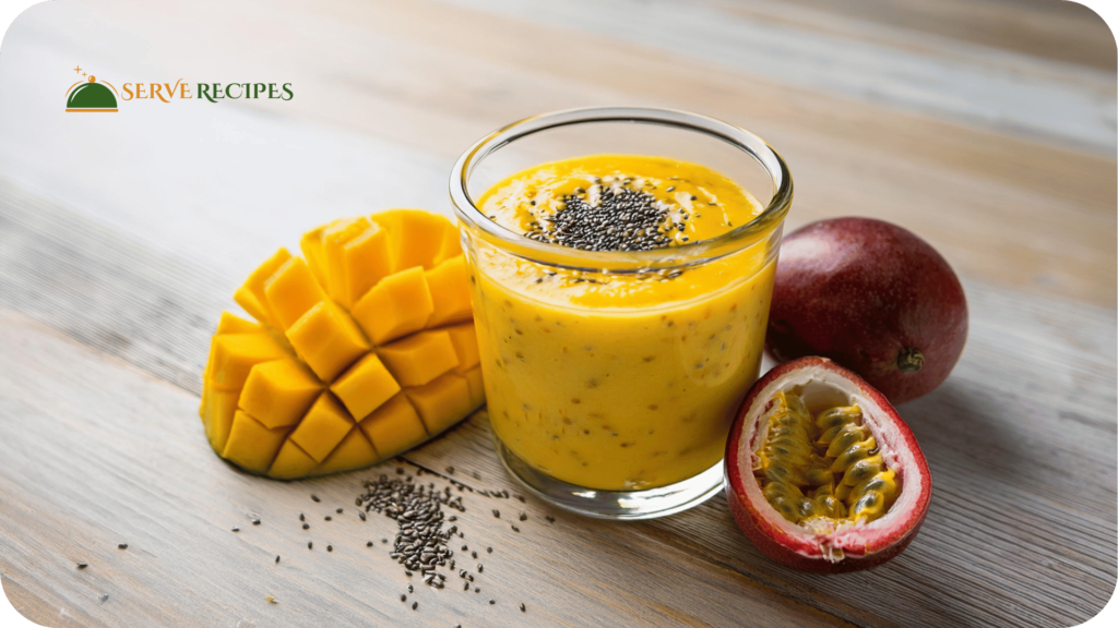 On a light wooden tabletop, a brilliant High-Protein Smoothies with mango garnished with fresh mango and chia seeds sits next to mango slices and passion fruit halves, served in a clear glass.