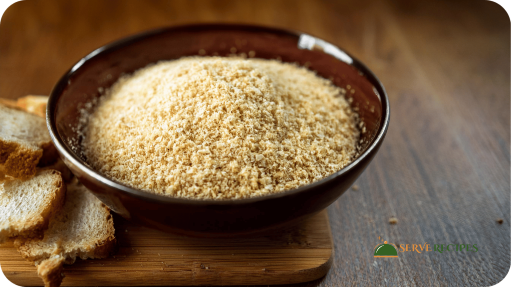 Golden, flaky homemade panko breadcrumbs in a bowl on a wooden kitchen counter.