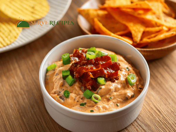 Rich and creamy buffalo chicken dip in a small white bowl, served with a side of crispy tortilla chips.