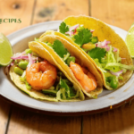 A plate of spicy shrimp tacos with creamy avocado-lime slaw garnished with lime wedges on a rustic wooden table, demonstrating the final results of a 30-minute recipe