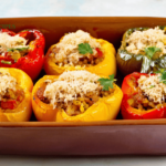 A colorful dish of low-carb stuffed bell peppers filled with quinoa and turkey, topped with melted cheese and garnished with fresh parsley, served in a ceramic baking dish.