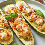 Keto Chicken and Zucchini Boats served on a rustic wooden table, garnished with fresh basil and melted mozzarella cheese.