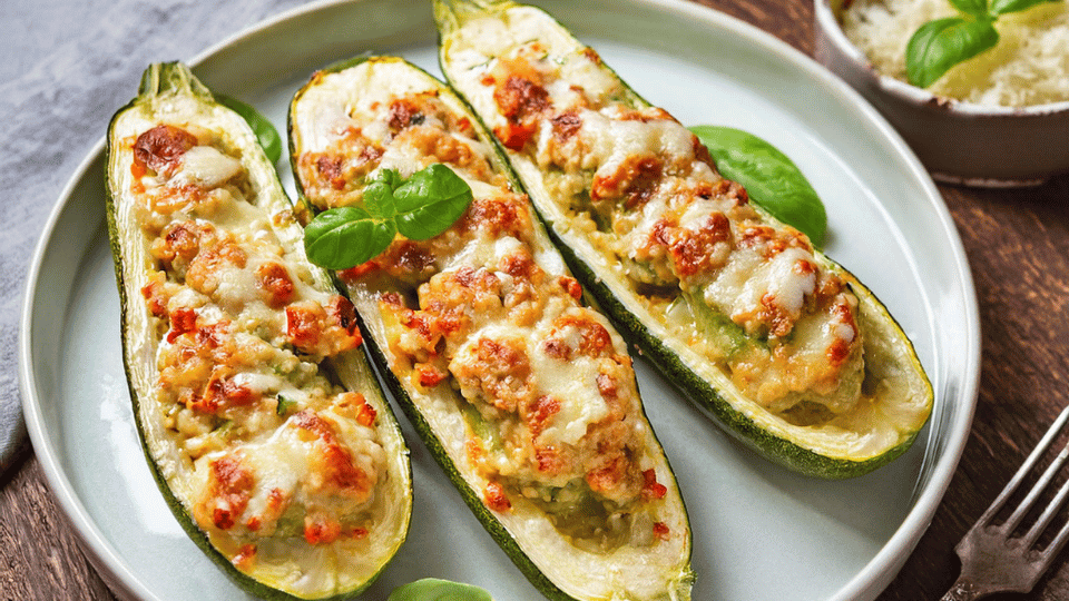 Keto Chicken and Zucchini Boats served on a rustic wooden table, garnished with fresh basil and melted mozzarella cheese.